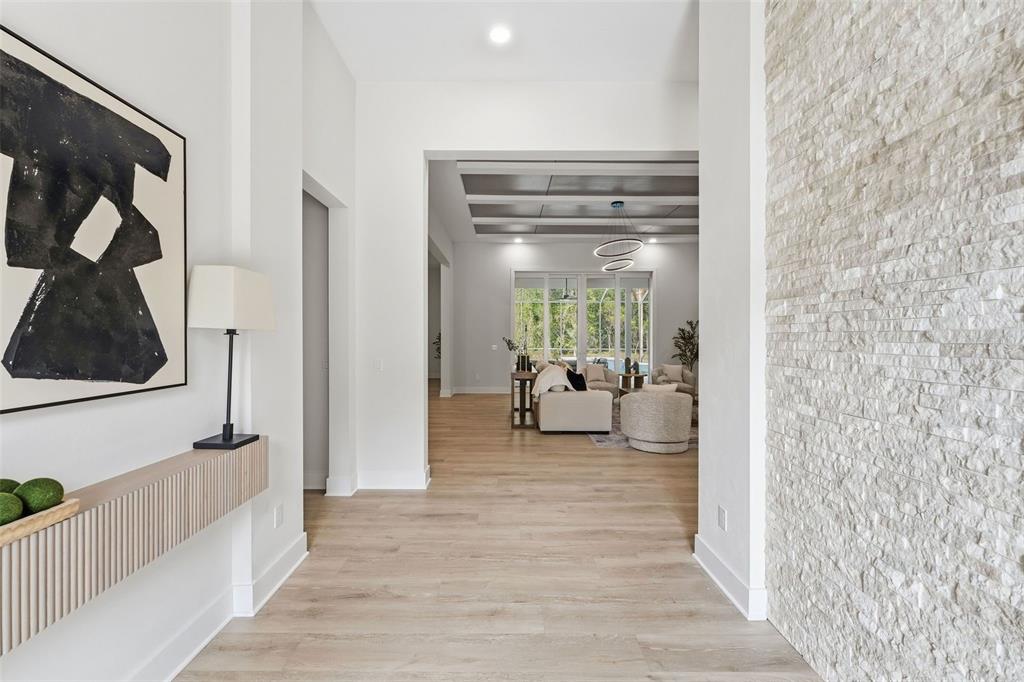 A bright entryway leads into a living room with light wood floors and stone walls — 5995 SW 124TH WAY, ARCHER, FL