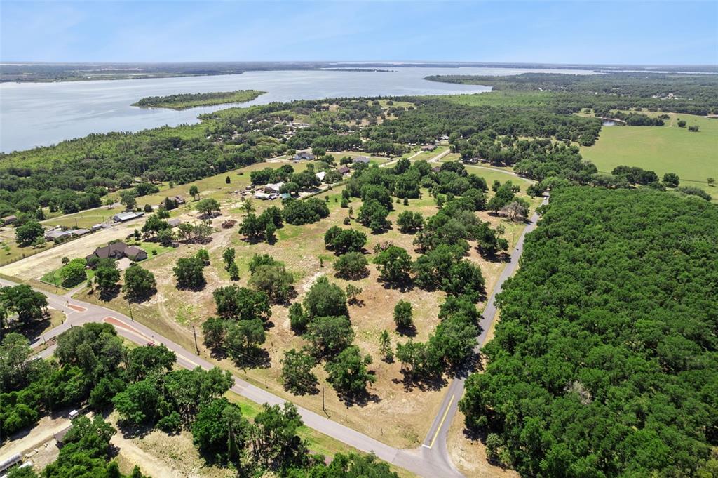 An aerial view shows a large, partially wooded plot of land near a lake — 0000 BERTSVILLE & GRIFFIN VIEW ROAD, LADY LAKE, FL