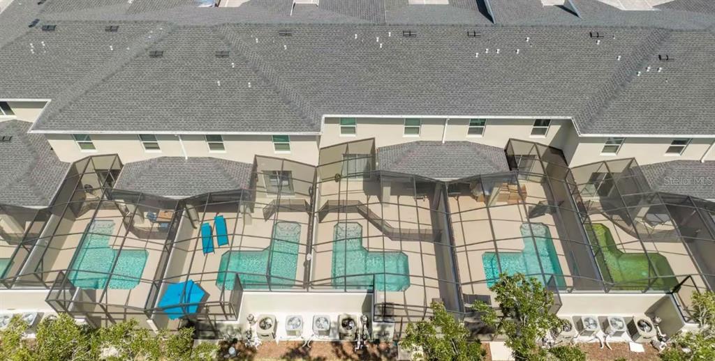 An aerial view shows a row of townhomes with screened-in patios and private swimming pools — 2513 READING TRAIL, KISSIMMEE, FL