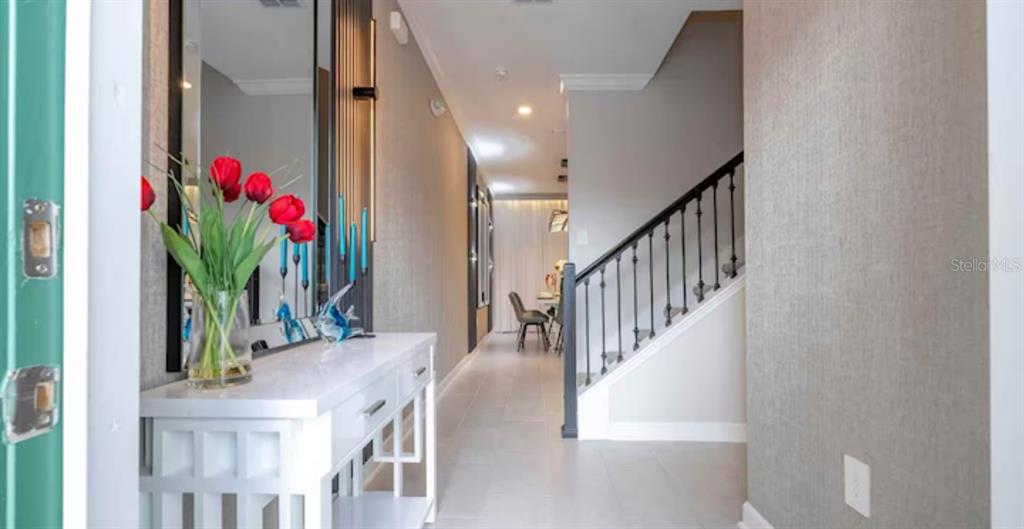 A white console table with red tulips sits in a hallway featuring a staircase — 2513 READING TRAIL, KISSIMMEE, FL