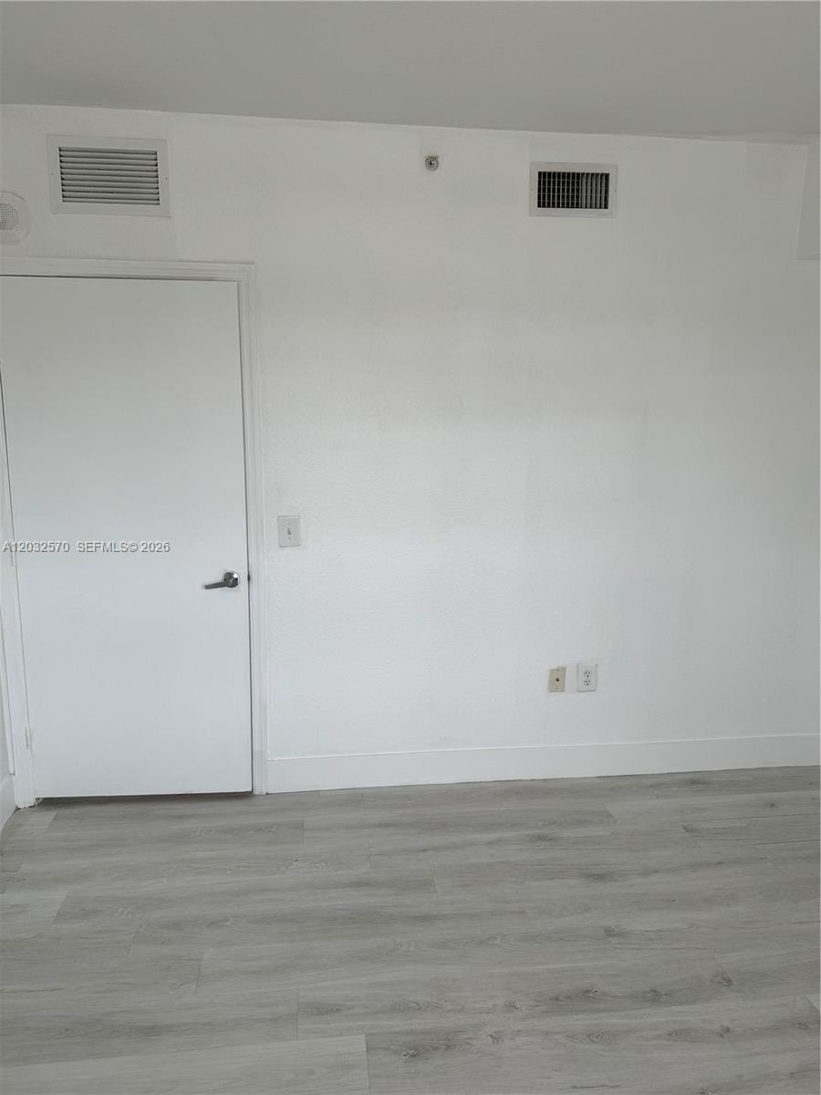 A white room features a closed door, light wood-look flooring, and two wall vents — 36 NW 6th Ave # 601, Miami FL 33128, MIAMI, FL