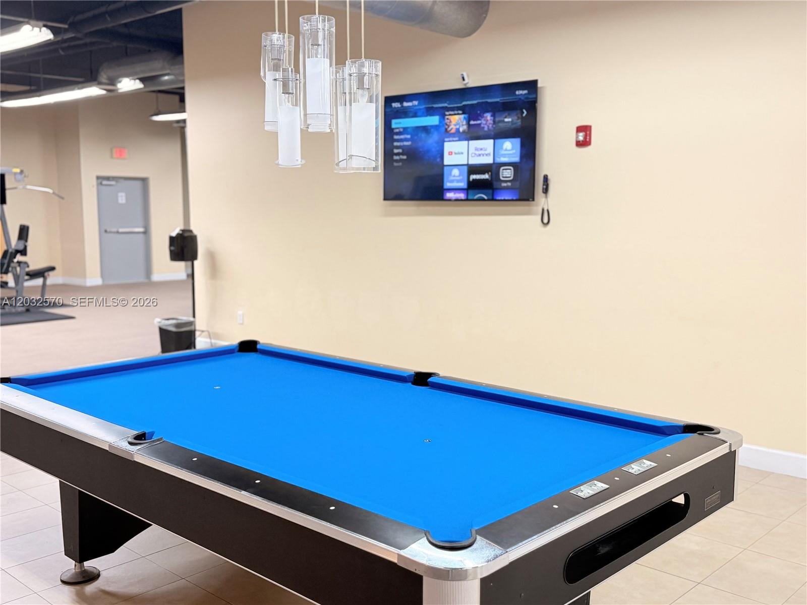 A blue pool table sits in a room with a wall-mounted television and pendant lights — 36 NW 6th Ave # 601, Miami FL 33128, MIAMI, FL