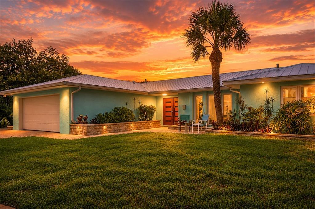 A teal, single-story house with a metal roof and palm tree at sunset — 6065 MANASOTA KEY ROAD, ENGLEWOOD, FL