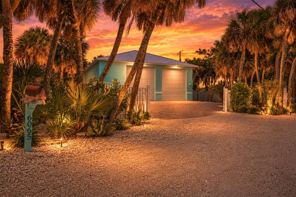 A turquoise detached two-car garage sits at the end of a gravel driveway at sunset — 6065 MANASOTA KEY ROAD, ENGLEWOOD, FL