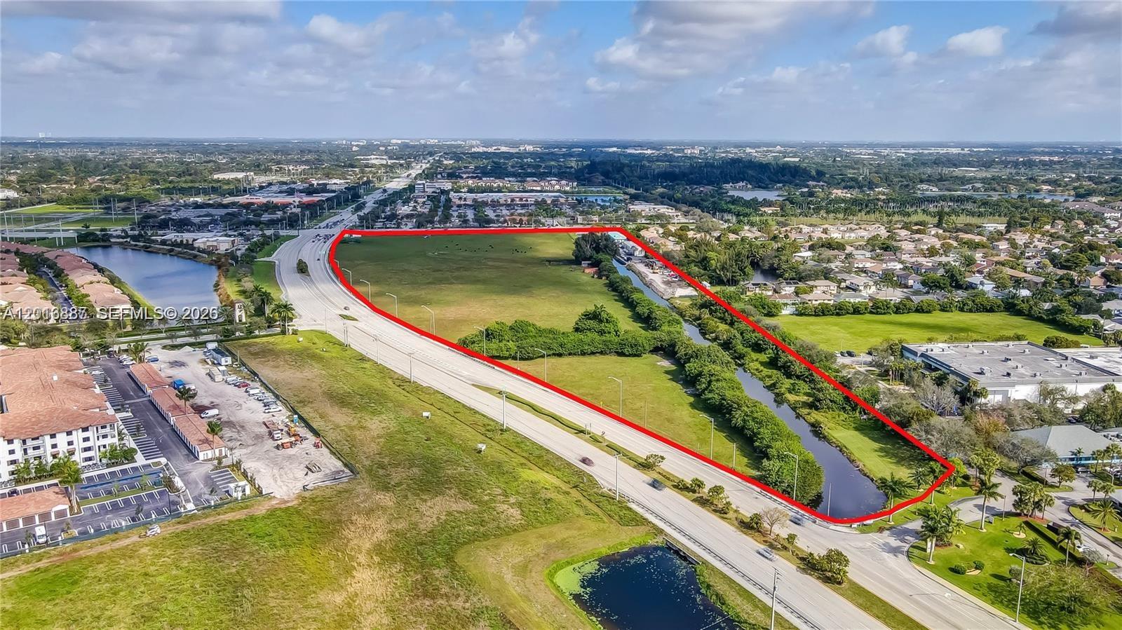 An aerial view shows a large, vacant plot of land outlined in red near a highway — 8020 Stirling Rd, Davie FL 33024, DAVIE, FL