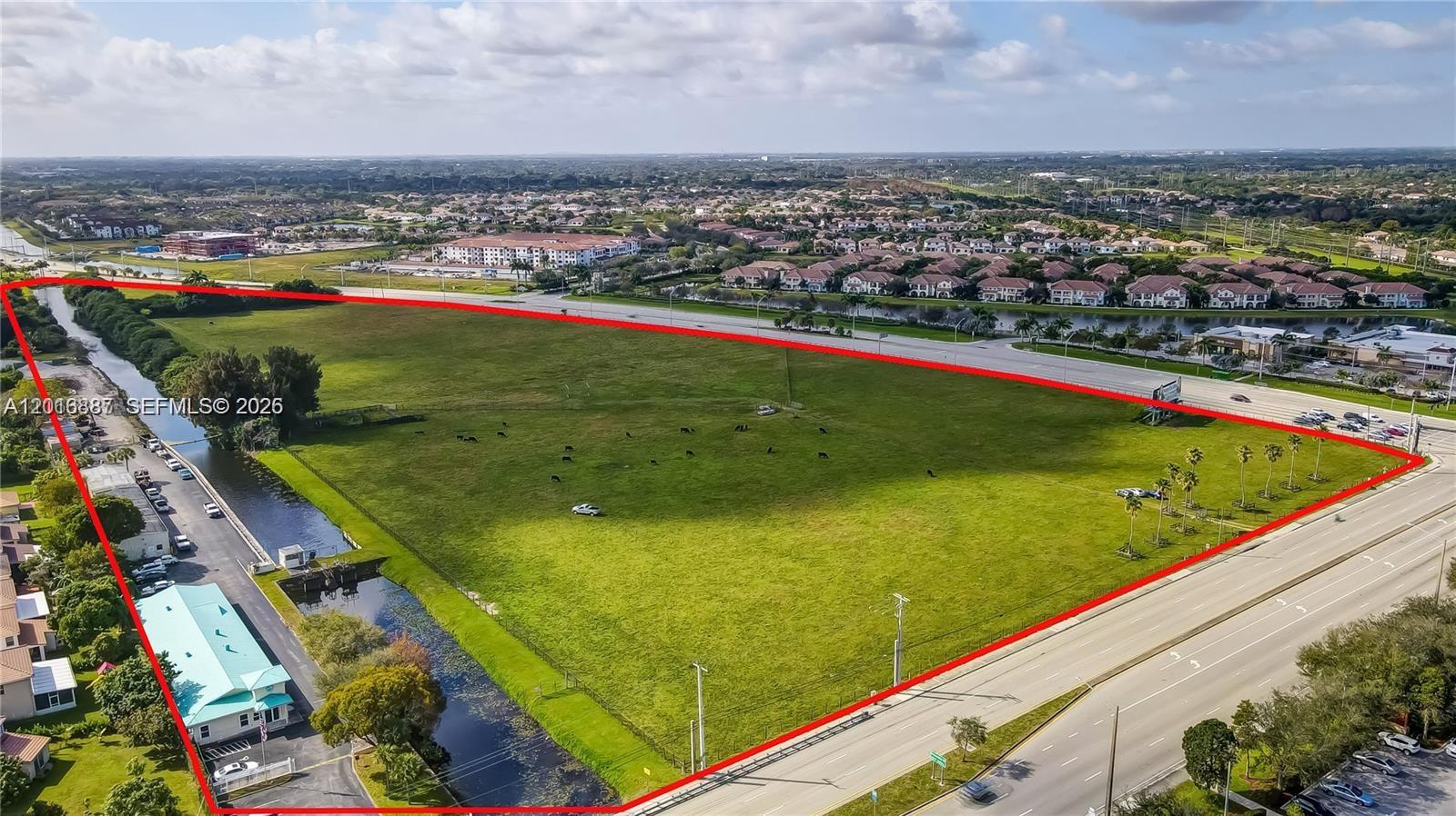 An aerial view shows a large, vacant grassy lot outlined in red beside a highway — 8020 Stirling Rd, Davie FL 33024, DAVIE, FL