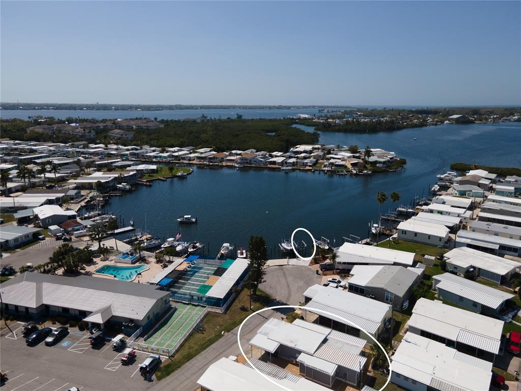 An aerial view shows a mobile home community with a pool, boat slips, and water — 2812 14TH STREET W, PALMETTO, FL