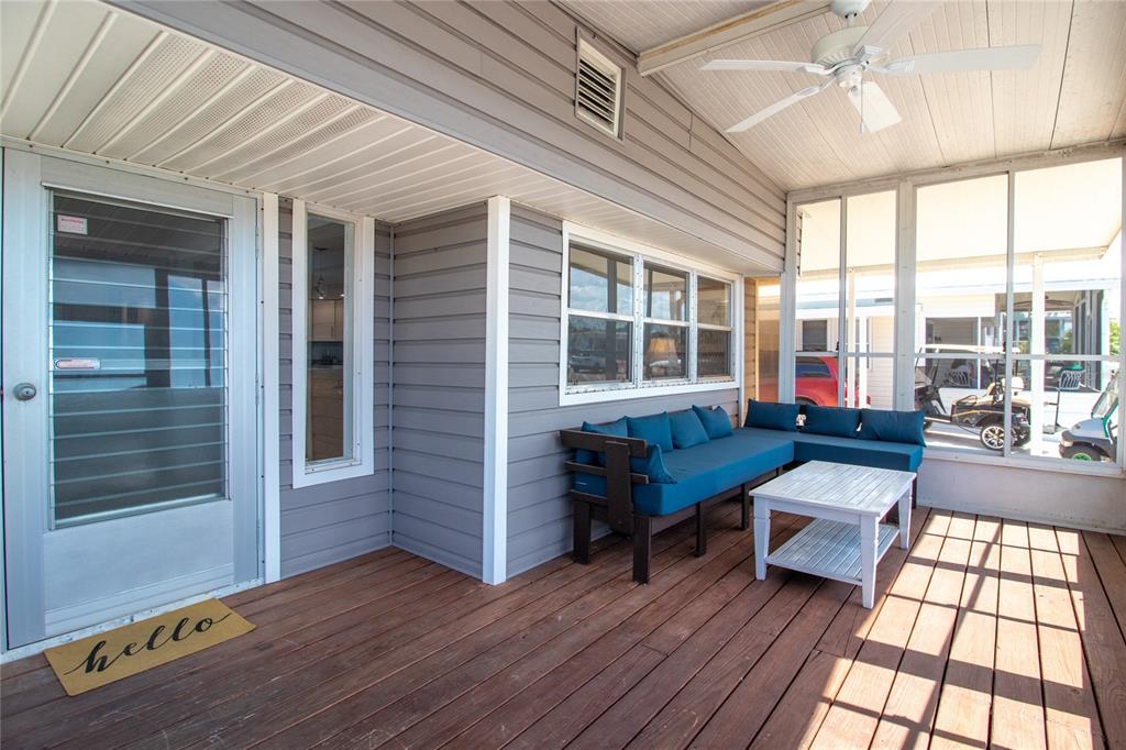 A covered wooden porch features a blue sectional sofa, a white coffee table, and a ceiling fan — 2812 14TH STREET W, PALMETTO, FL