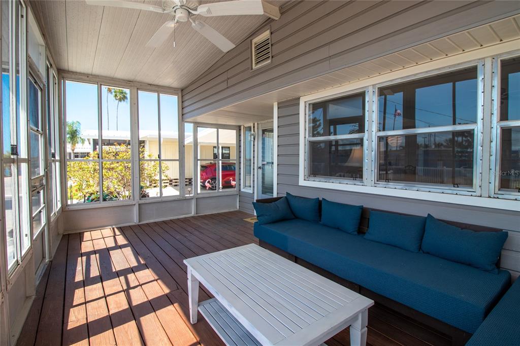 A screened-in porch with a wooden deck, a blue sofa, and a white coffee table — 2812 14TH STREET W, PALMETTO, FL
