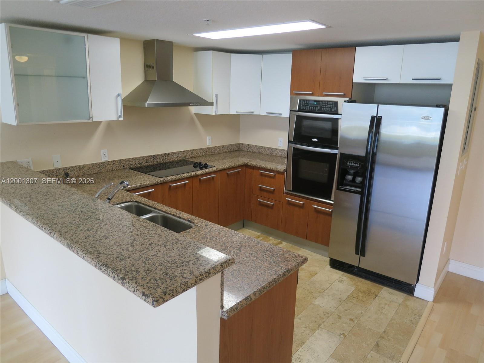 A kitchen features wood cabinets, granite countertops, stainless steel appliances, and a tile floor — 170 SE 14 ST # 1507, Miami FL 33131, MIAMI, FL