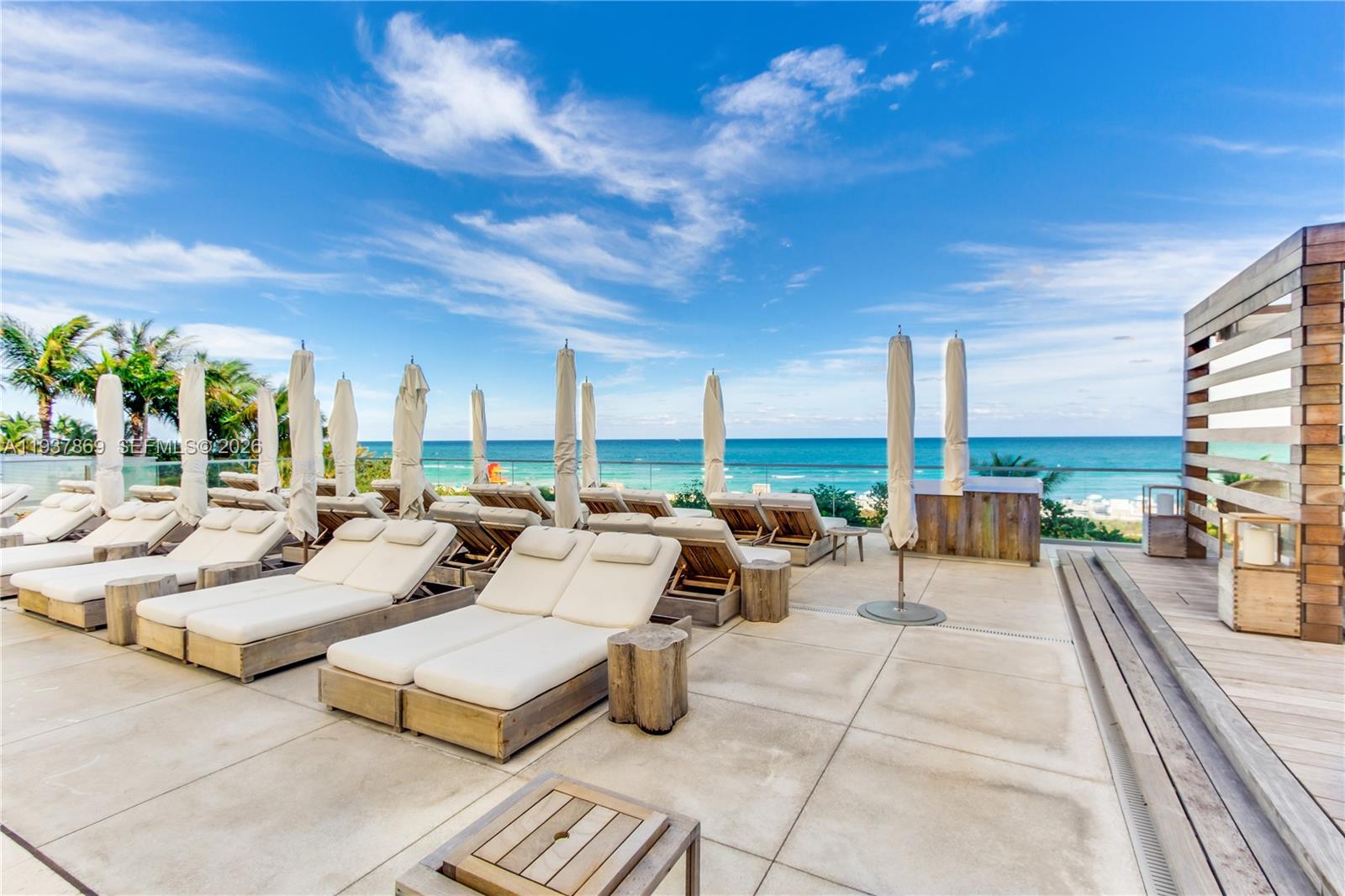 An outdoor pool deck features rows of lounge chairs with umbrellas overlooking the ocean — 2301 COLLINS AV # 1026, Miami Beach FL 33139, MIAMI BEACH, FL