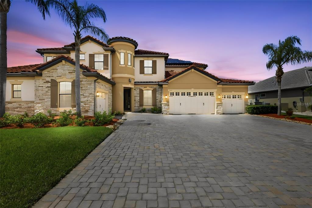 A two-story Mediterranean-style house with a stone facade, tile roof, and a paved driveway — 5229 WATERSIDE VISTA LANE, ST CLOUD, FL