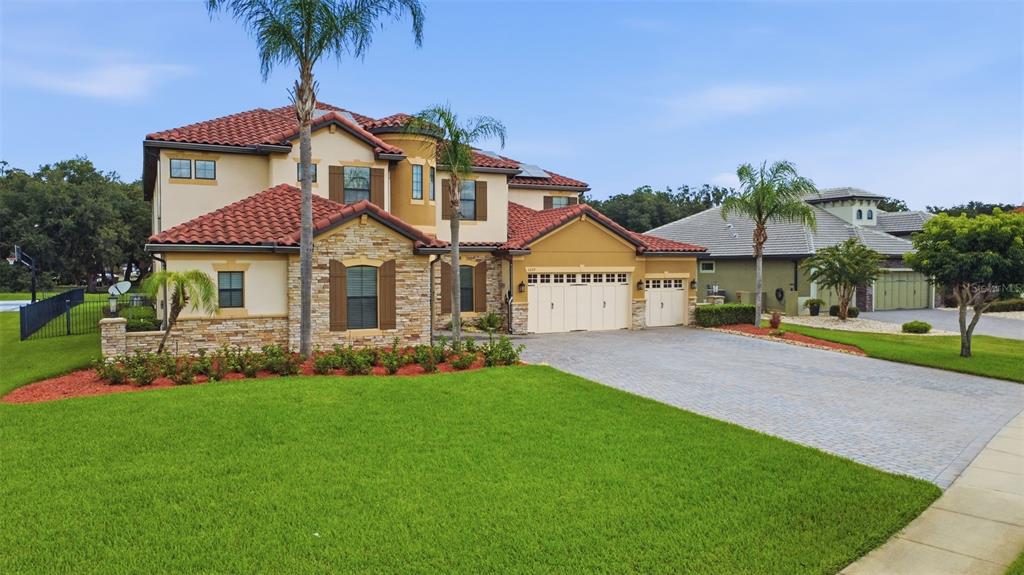 A two-story stucco house with a red tile roof, stone accents, and a paved driveway — 5229 WATERSIDE VISTA LANE, ST CLOUD, FL