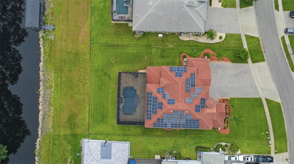 An aerial view shows a house with a tiled roof, solar panels, and a screened pool — 5229 WATERSIDE VISTA LANE, ST CLOUD, FL