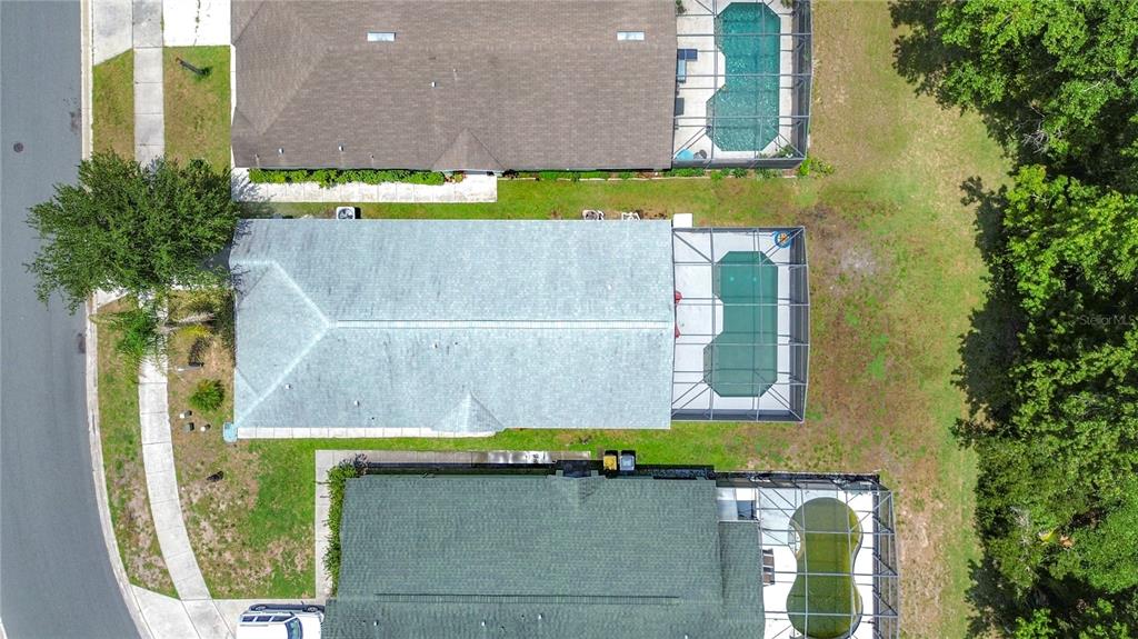 An aerial view shows three suburban houses with screened-in swimming pools and backyard lawns — 1501 ROYAL RIDGE DRIVE, DAVENPORT, FL