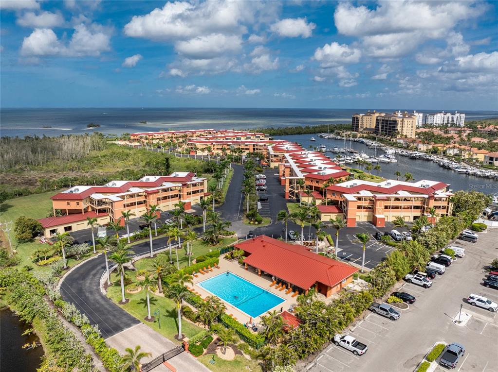An aerial view shows a multi-story apartment complex with a swimming pool and marina — 3250 SOUTHSHORE DRIVE UNIT 53B, PUNTA GORDA, FL