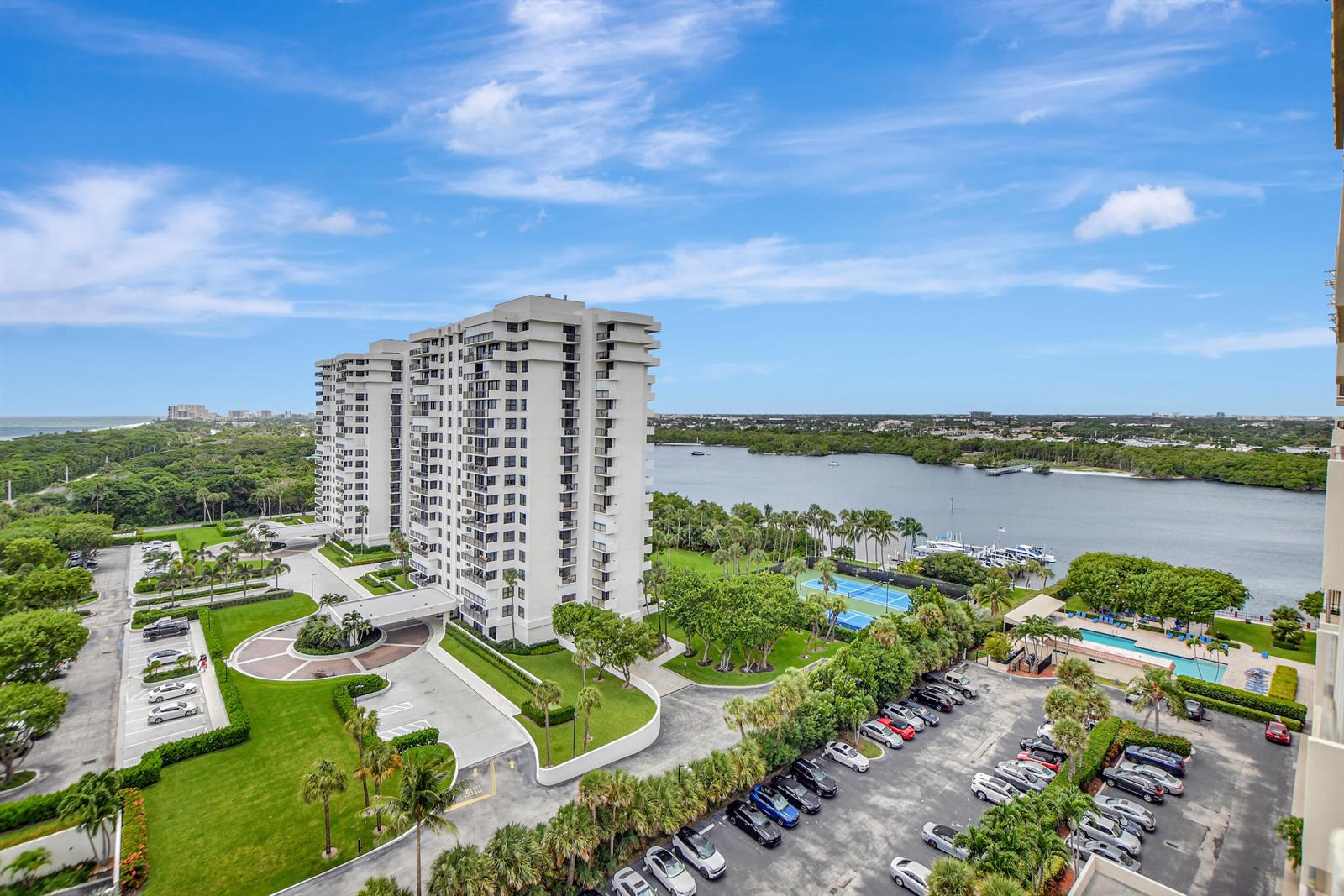 An aerial view shows a tall residential building with a parking lot, tennis courts, and pool — 2121 N Ocean Boulevard # 1405e, Boca Raton FL 33431, BOCA RATON, FL