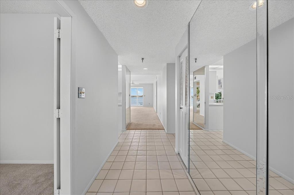 A tiled hallway leads to a carpeted living area with mirrored closet doors on the right — 8001 SAILBOAT KEY BOULEVARD S UNIT 201, ST PETE BEACH, FL