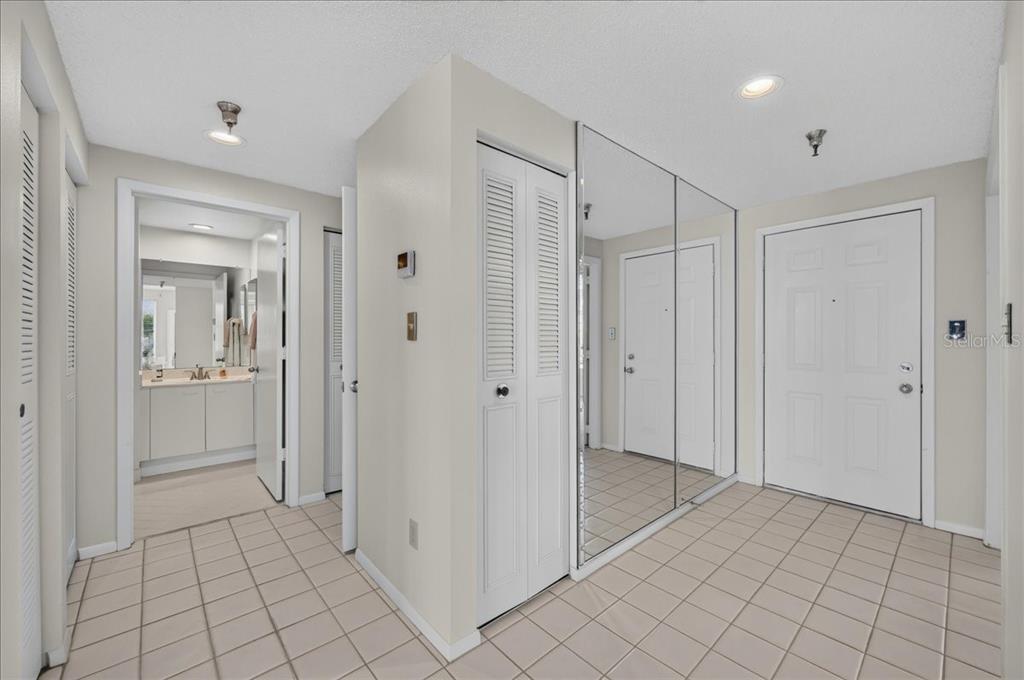 An entryway with tiled flooring, a mirrored closet, and a doorway leading to a bathroom — 8001 SAILBOAT KEY BOULEVARD S UNIT 201, ST PETE BEACH, FL