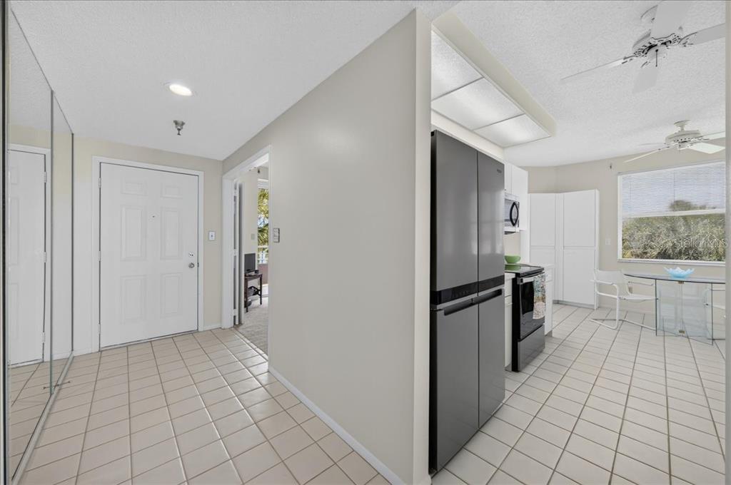 A tiled entryway leads to a kitchen with a stainless steel refrigerator and dining area — 8001 SAILBOAT KEY BOULEVARD S UNIT 201, ST PETE BEACH, FL