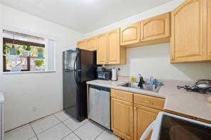 A kitchen features light wood cabinets, a black refrigerator, a dishwasher, and a window — 504 Gardens Drive # 203, Pompano Beach FL 33069, POMPANO BEACH, FL