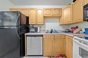 A kitchen featuring light wood cabinets, a black refrigerator, a stainless dishwasher, and white countertops — 504 Gardens Drive # 203, Pompano Beach FL 33069, POMPANO BEACH, FL