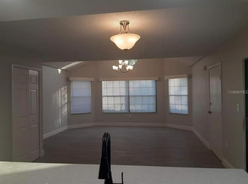 A view from a kitchen counter looking into a living room with large windows — 3123 FOX SQUIRREL DR UNIT B, KISSIMMEE, FL