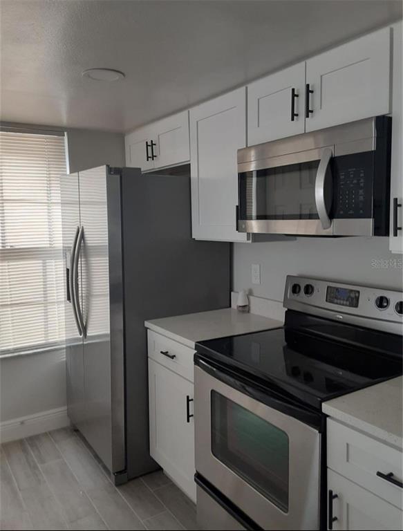 A kitchen features white cabinets, stainless steel appliances, and light-colored tile flooring — 3123 FOX SQUIRREL DR UNIT B, KISSIMMEE, FL