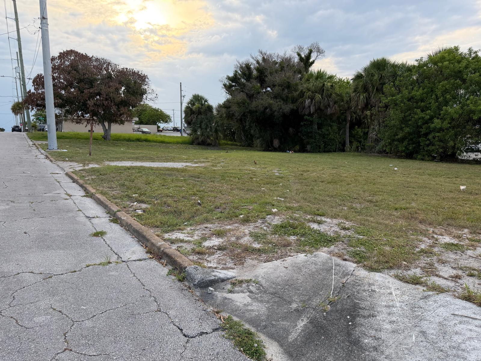 A vacant, grassy lot sits adjacent to a cracked concrete sidewalk and utility pole — 408 Avenue E, Fort Pierce FL 34950, FORT PIERCE, FL
