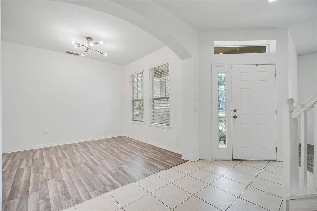 An entryway with tile flooring leads into a dining area featuring wood-look laminate flooring — 3214 HOPEWELL DRIVE, KISSIMMEE, FL