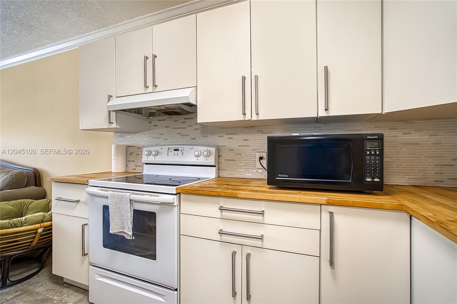 A kitchen features white cabinets, a white electric range, a black microwave, and wood countertops — 173 Ellesmere C # 173, Deerfield Beach FL 33442, DEERFIELD BEACH, FL