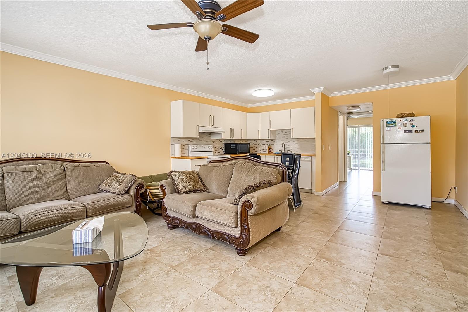 This living room features tile flooring, a ceiling fan, and an open-concept kitchen — 173 Ellesmere C # 173, Deerfield Beach FL 33442, DEERFIELD BEACH, FL