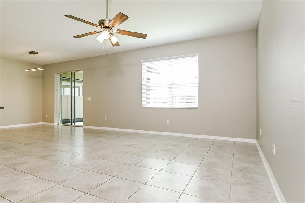 An empty living room features light tile flooring, a ceiling fan, and a sliding glass door — 10313 BERRYESSA AVENUE, RIVERVIEW, FL