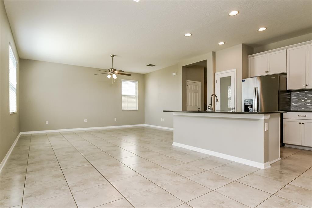 An open-concept kitchen and living area with tile flooring, white cabinets, and a kitchen island — 10313 BERRYESSA AVENUE, RIVERVIEW, FL