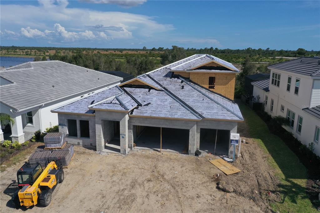 A single-story house under construction features concrete block walls, a garage, and a dumpster nearby — 11245 BLISSBY STREET, VENICE, FL