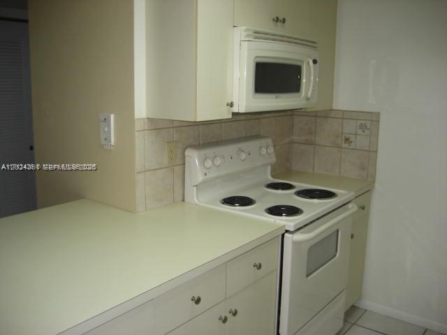 A kitchen features white cabinets, a white electric stove, and a mounted microwave — 10744 N Kendall # 18, Miami FL 33176, MIAMI, FL