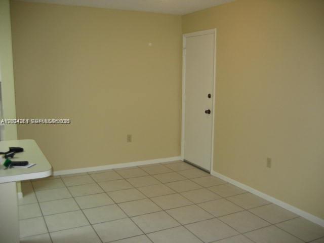 An empty room with beige walls, white tile flooring, and a single white door — 10744 N Kendall # 18, Miami FL 33176, MIAMI, FL