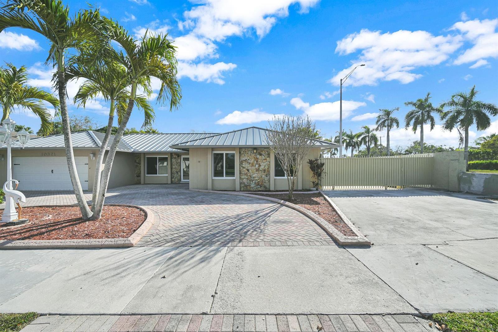 A single-story house features a metal roof, stone accents, and a paved circular driveway — 10321 SW 116th Avenue, Miami FL 33176, MIAMI, FL