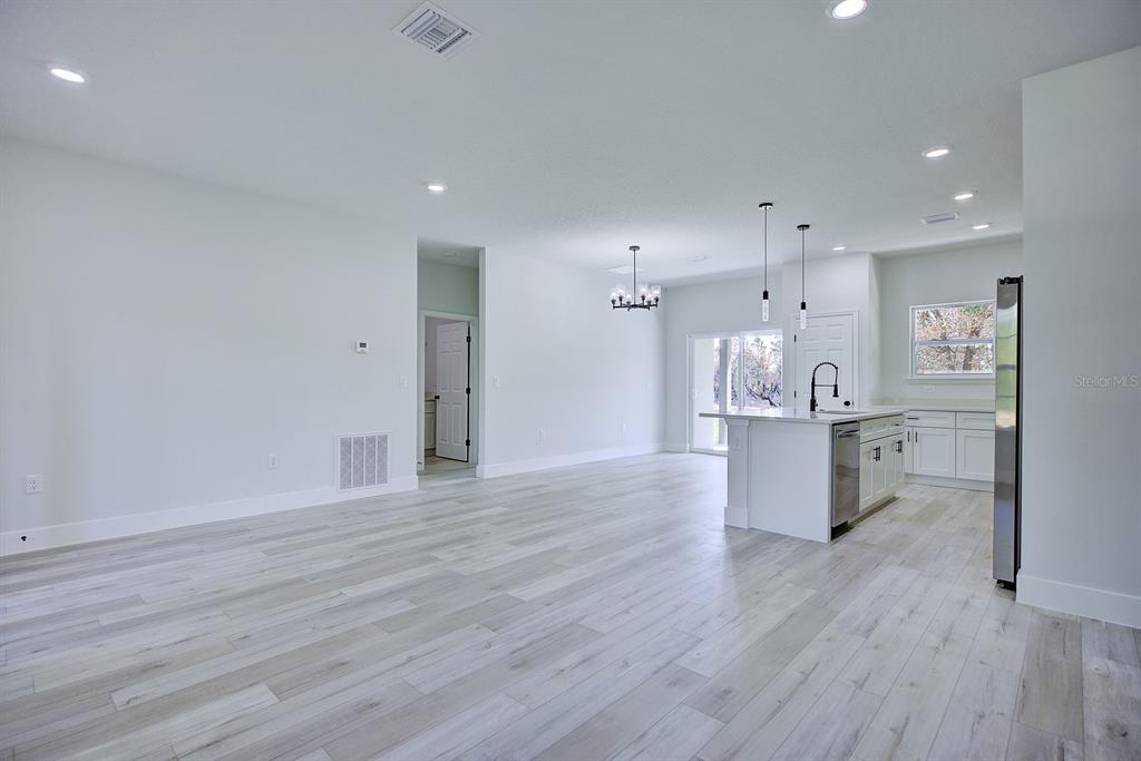 An open-concept kitchen and living area features white cabinetry, a center island, and light-colored flooring — 5230 SAN JUAN DRIVE, SEBRING, FL