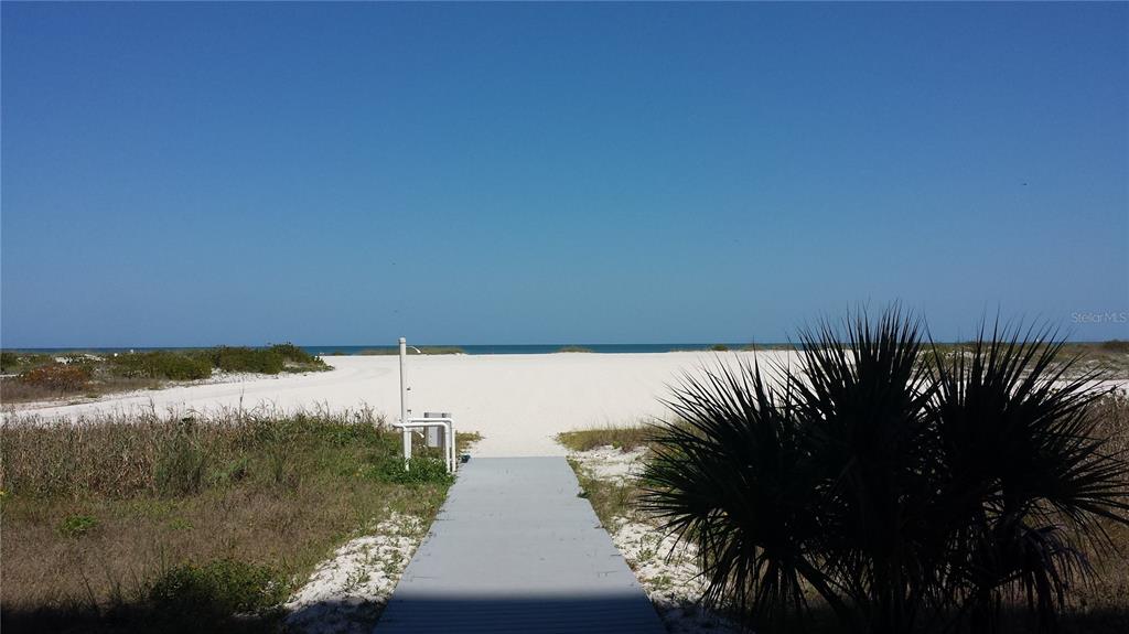 A wooden boardwalk leads through sand dunes toward the ocean under a clear blue sky — 1270 GULF BOULEVARD UNIT 302, CLEARWATER BEACH, FL