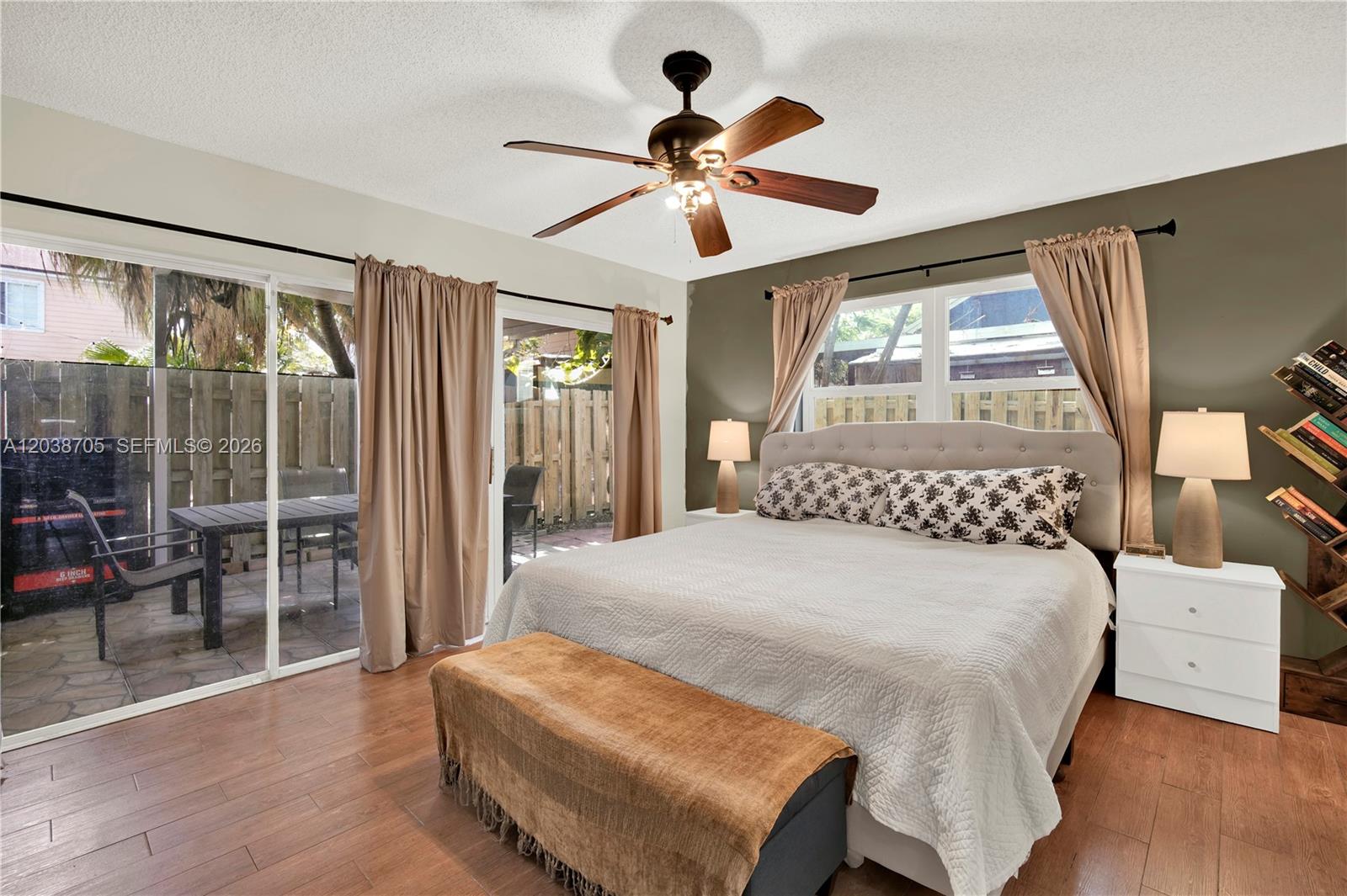A bedroom features a bed, a ceiling fan, sliding glass doors, and wood-look flooring — 10003 SW 223rd Ter, Cutler Bay FL 33190, CUTLER BAY, FL