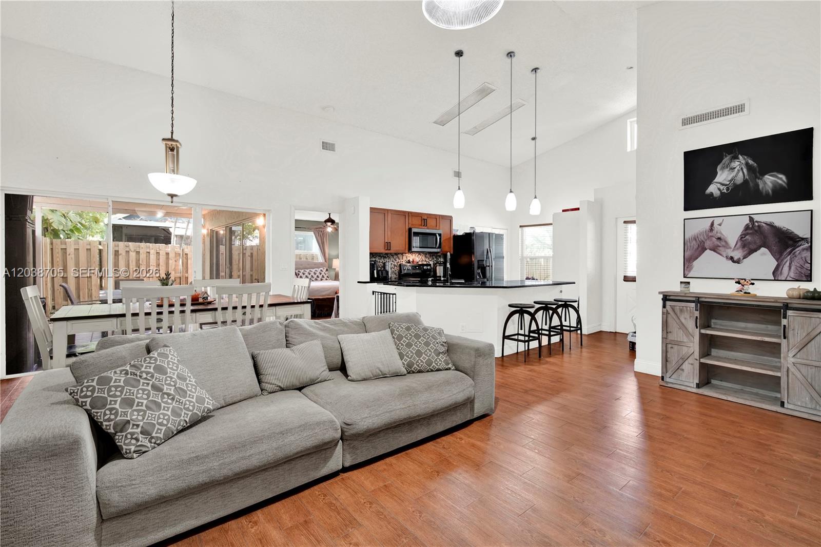 A living room with a gray sofa, wood floors, and an open kitchen with bar seating — 10003 SW 223rd Ter, Cutler Bay FL 33190, CUTLER BAY, FL