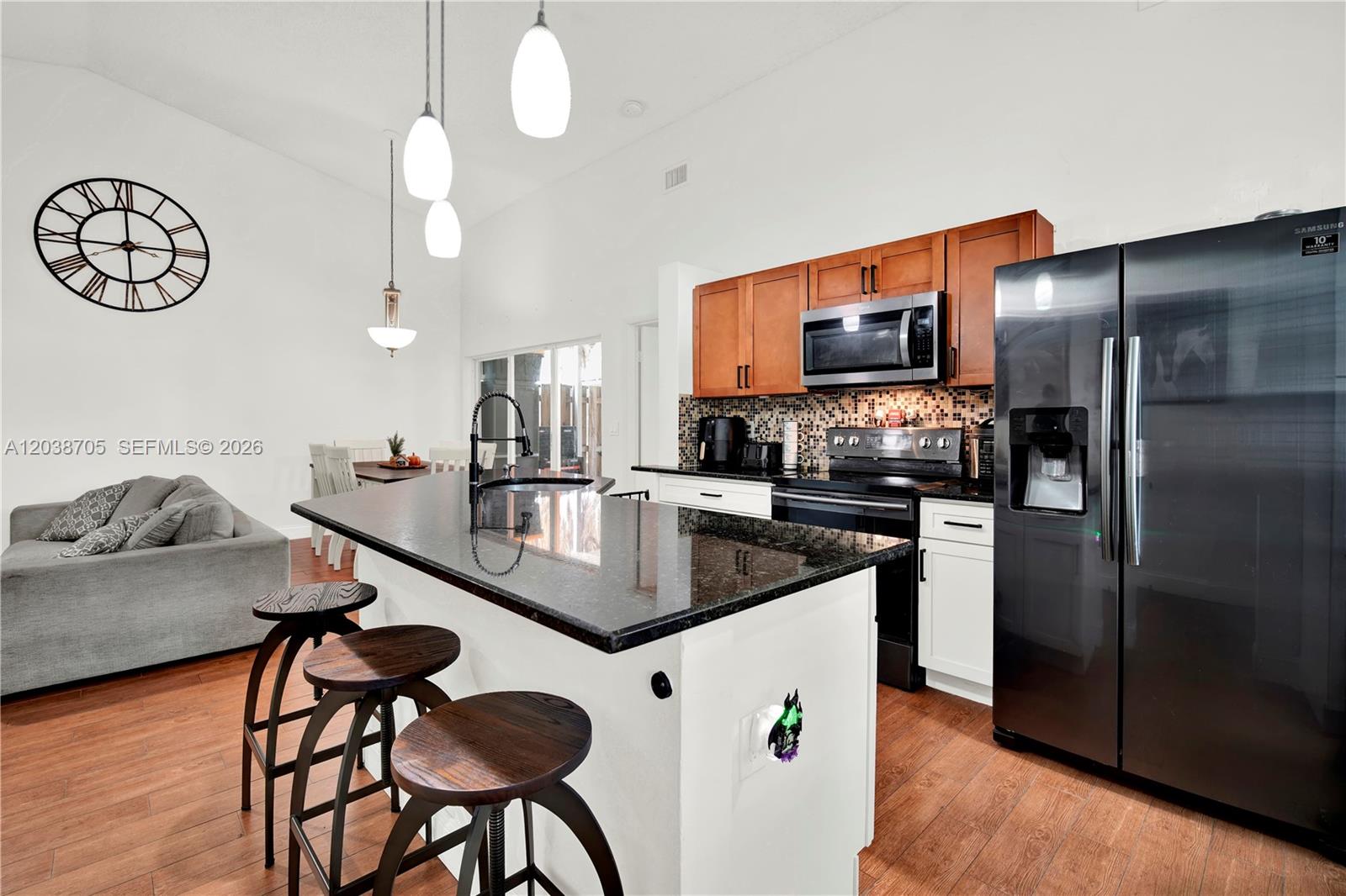 A kitchen features a black granite island, white lower cabinets, wood upper cabinets, and stainless appliances — 10003 SW 223rd Ter, Cutler Bay FL 33190, CUTLER BAY, FL