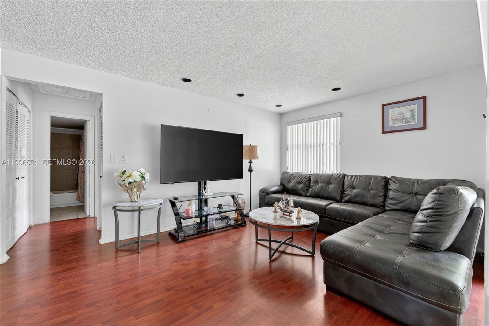 A living room features a black sectional sofa, a television on a stand, and wood flooring — 20015 NE 3rd Ct # 6, Miami FL 33179, MIAMI, FL
