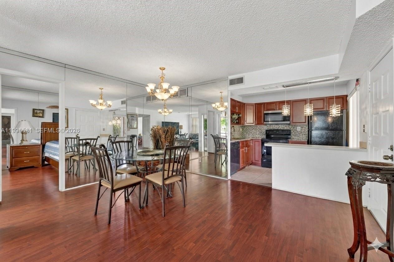 A dining area with wood floors and mirrored walls opens to a kitchen with dark cabinets — 20015 NE 3rd Ct # 6, Miami FL 33179, MIAMI, FL