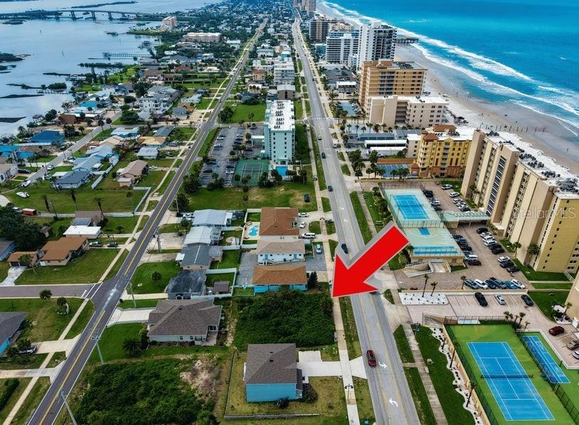 An aerial view shows a coastal neighborhood with a red arrow pointing to a vacant lot — 3826 S ATLANTIC AVENUE, DAYTONA BEACH SHORES, FL