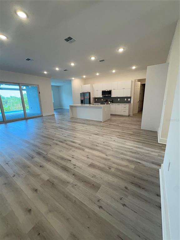 An open-concept kitchen with white cabinets and a central island overlooks a spacious living area — 14681 KEYSTONE BOULEVARD, PORT CHARLOTTE, FL