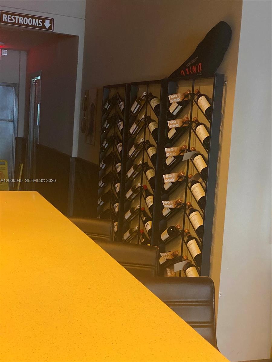A wine rack filled with bottles stands next to a bar counter and restroom sign — 9511 S DIXIE HWY, Pinecrest FL 33156, PINECREST, FL
