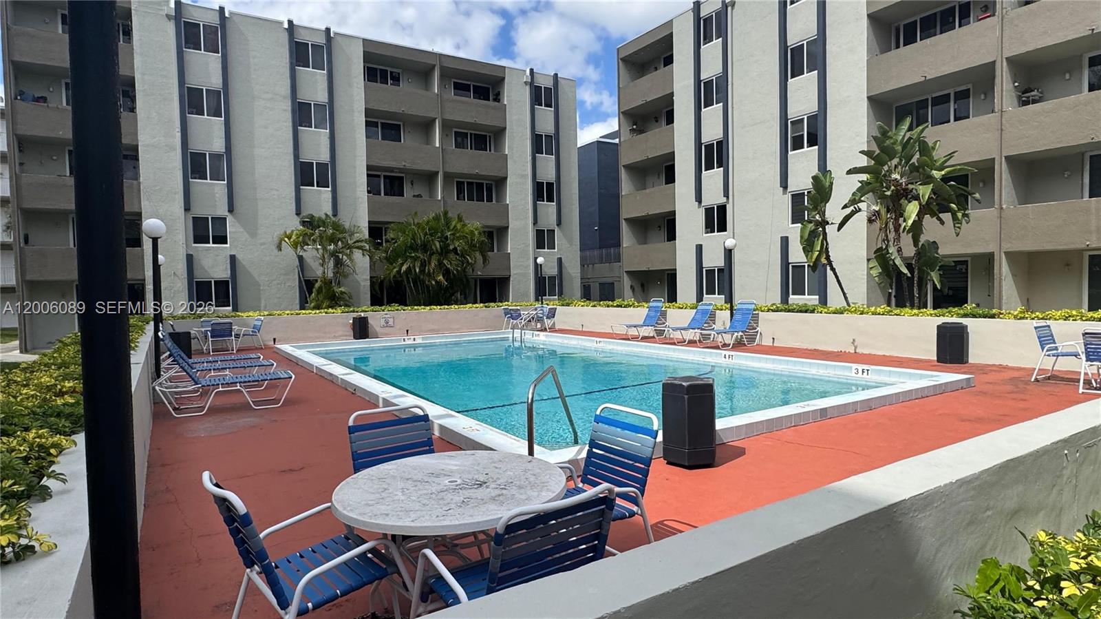 An outdoor swimming pool is surrounded by lounge chairs and a table on a patio — 10090 NW 80th Ct # 1203, Hialeah Gardens FL 33016, HIALEAH GARDENS, FL