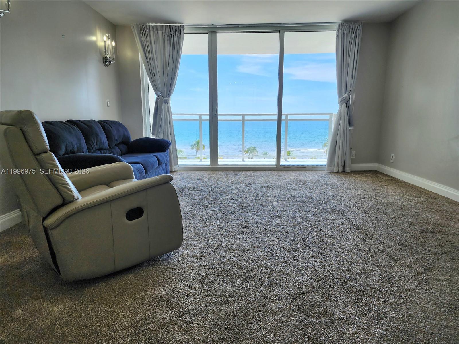 A living room features carpeted flooring, a sofa, a recliner, and floor-to-ceiling ocean views — 2030 S Ocean Dr # 515, Hallandale Beach FL 33009, HALLANDALE BEACH, FL